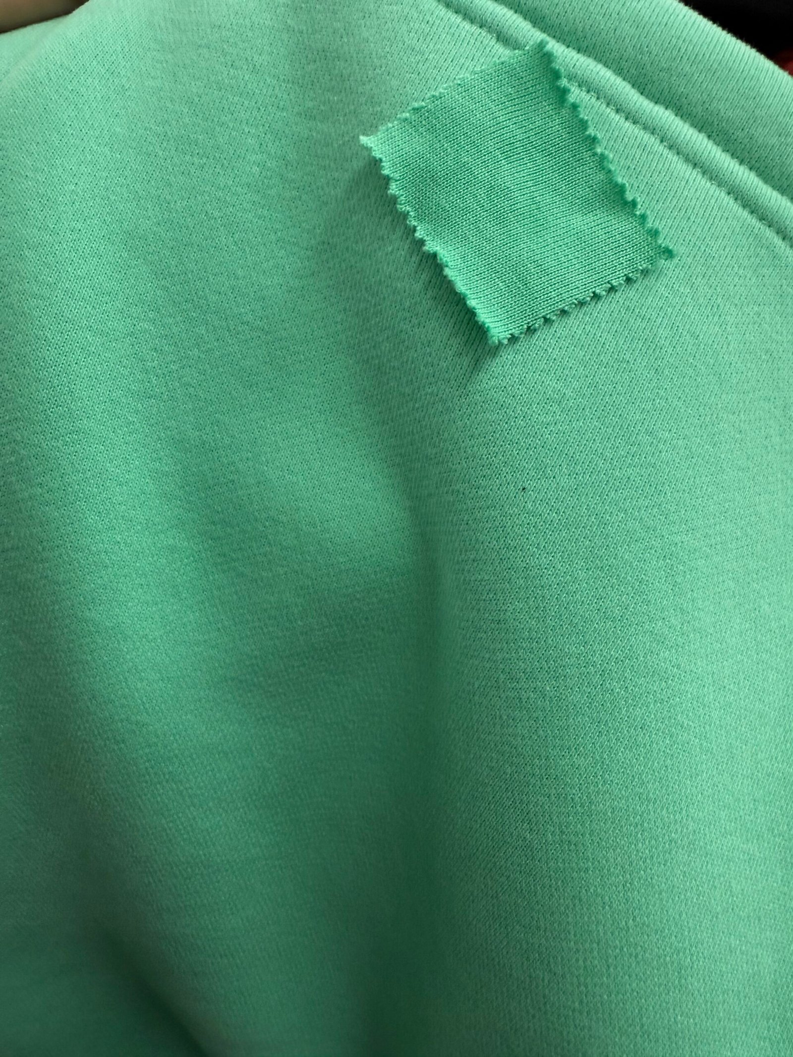 Pre-production sample with signed fabric label showing GSM weight verification before bulk clothing manufacturing